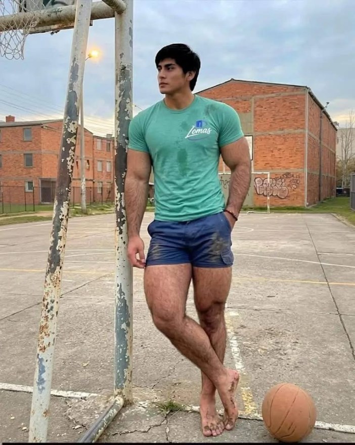 Muscular man leaning against a pole.